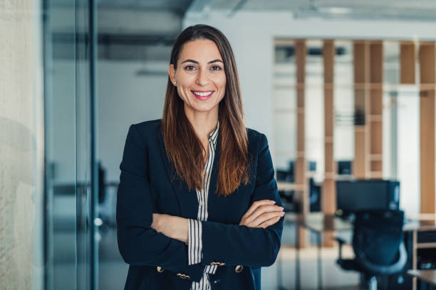 Shot of beautiful smiling businesswoman standing with crossed arms in her office and looking at camera.