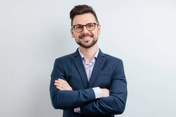 Close up portrait of a cheerful man in glasses and dark blue suit. Isolated on grey background